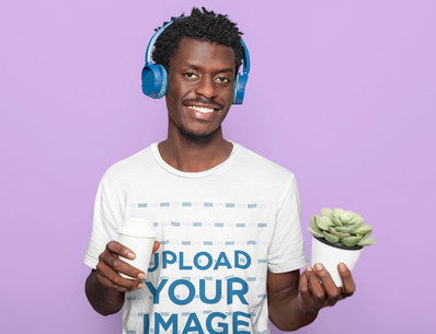 Round Neck Tee Mockup of a Smiling Man With Afro Hair Holding a Paper Cup and a Plant