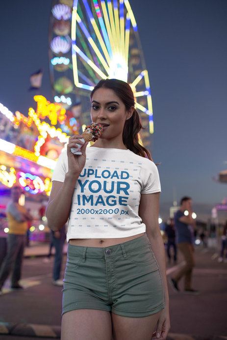 Woman Wearing a T-Shirt Mockup Having an Ice at an Amusement Park