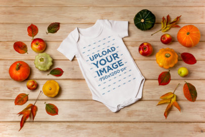 Mockup of a Onesie Lying on a Wooden Surface and Surrounded by Fall Decorations m19744 r-el2