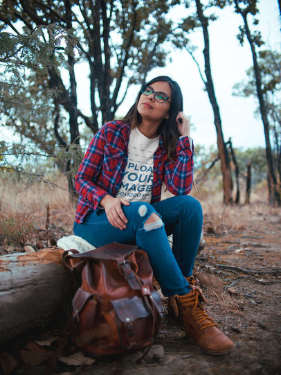 Woman with Glasses Wearing a T-Shirt Mockup Sitting on a Tree Trunk a19032