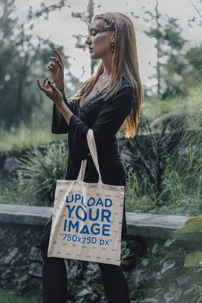 Sublimated Tote Bag Mockup of a Woman Wearing a Dark Forest-Inspired Outfit
