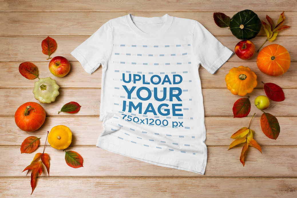 Mockup of a T-Shirt Lying on a Wooden Surface Featuring Fall Decorations