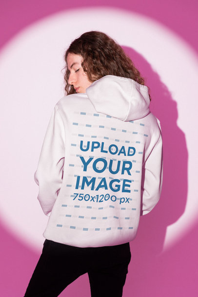 Back-View Hoodie Mockup Featuring a Curly-Haired Man Posing Against a Pink Light m28993
