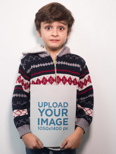 Surprised Boy Holding a Book Mockup Against a White Wall
