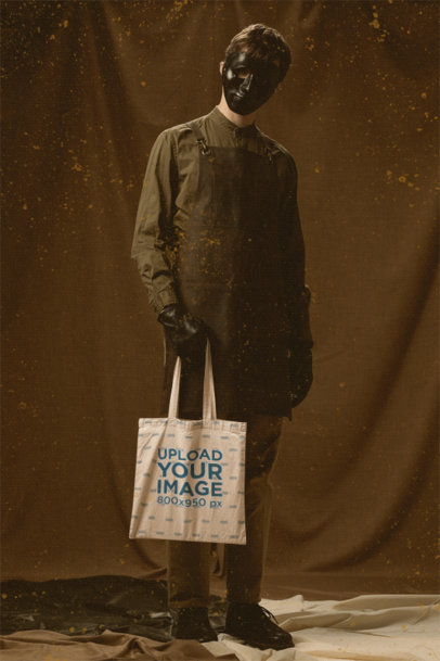 Tote Bag Mockup Featuring a Man with a Scary Halloween Mask at a Studio