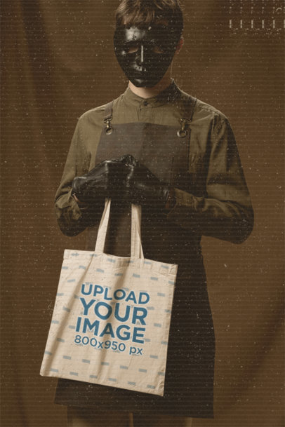 Mockup of a Man with a Creepy Halloween Mask Holding a Tote Bag