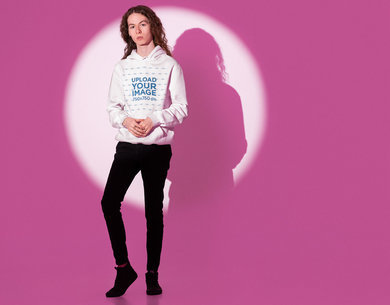 Hoodie Mockup of a Long-Haired Man Posing at a Studio With a Pink Light
