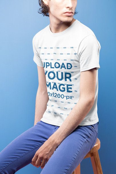 Closeup of a Dude Wearing a Short Sleeved T-Shirt Mockup Against a Blue Background