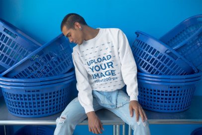 Man Wearing a Crewneck Sweatshirt Template Sitting Between Baskets at the Laundry a19704