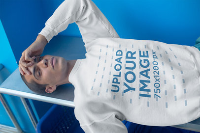 Side Shot of a Man Wearing a Crewneck Sweater Mockup in a Blue Room