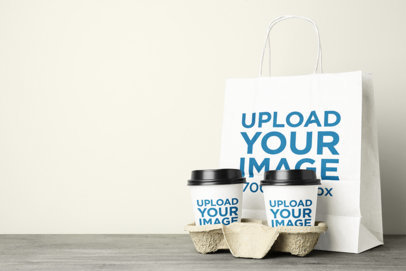 Mockup of a Paper Bag Placed Behind Two Paper Cups