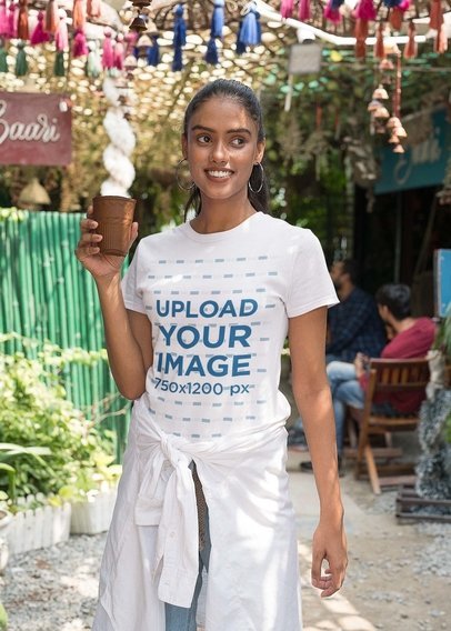 Gildan Tee Mockup Featuring a Happy Woman Holding a Ceramic Glass in the Street