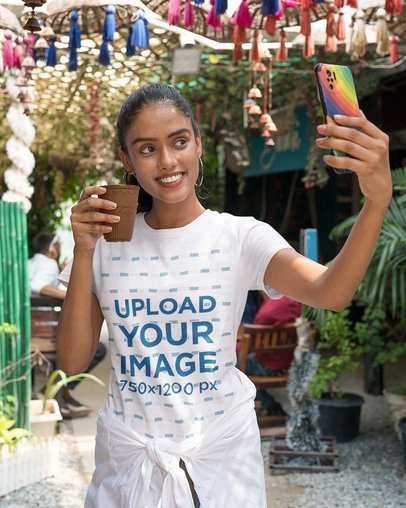 Mockup of a Gildan T-Shirt Featuring a Woman Taking a Selfie While Holding a Glass in the Street