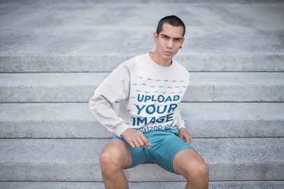 Serious Man Wearing a Crewneck Sweatshirt Mockup Sitting on Concrete Stairs a19708
