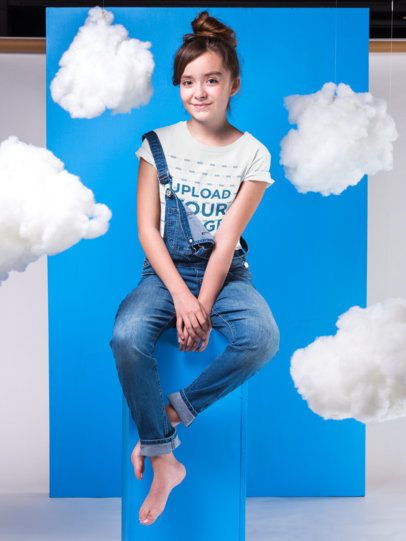  Mockup of a Girl Wearing a T-Shirt  Standing Against a Blue Cardboard with Clouds Hanging