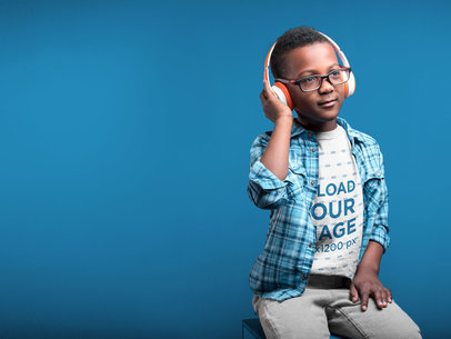 Kid Wearing a Tshirt Mockup Listening to Music in a Light Blue Room