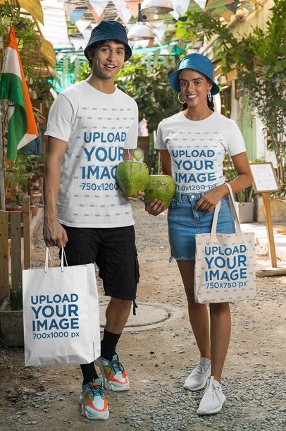 Gildan T-Shirt and Tote Bag Mockup Featuring a Happy Couple With Coconuts and a Paper Bag