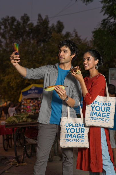 Sublimated Tote Bag Mockup of a Happy Couple Taking a Selfie with Street Food Snacks