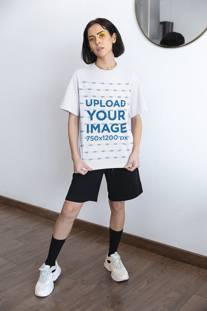 T-Shirt Mockup Featuring a Serious Woman Posing Against a White Wall 