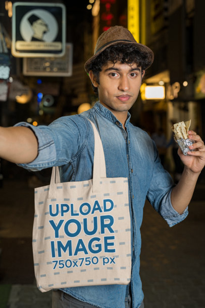 Tote Bag Mockup of a Man Taking a Selfie with a Fast Food Snack