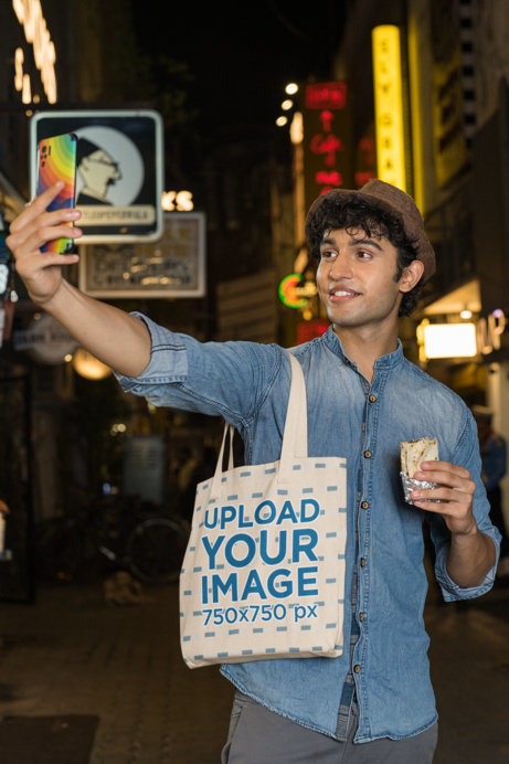Tote Bag Mockup Featuring a Smiling Man Taking a Selfie
