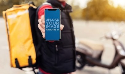 Mockup of a Delivery Man Holding an iPhone 13