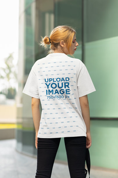 Back-View T-Shirt Mockup Featuring a Woman Standing on a Street
