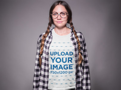 Nerd Woman Wearing a T-Shirt Mockup and Glasses in a Gray Room