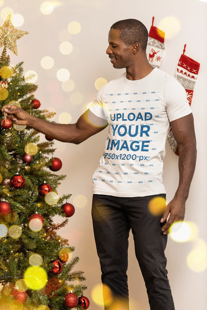 Bella Canvas T-Shirt Mockup of a Man Placing a Christmas Ball on a Tree