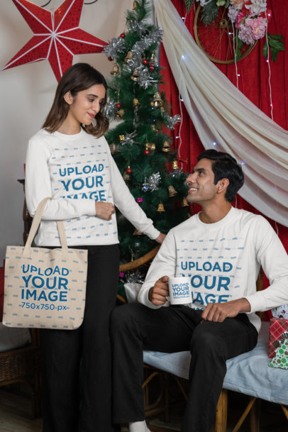 Sweatshirt Mockup of a Woman Carrying a Tote Bag and a Man With a Mug While Posing in a Christmas Setting