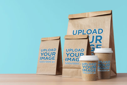 Mockup of Three Food Paper Bags and Two Paper Cups Placed on a Wooden Table