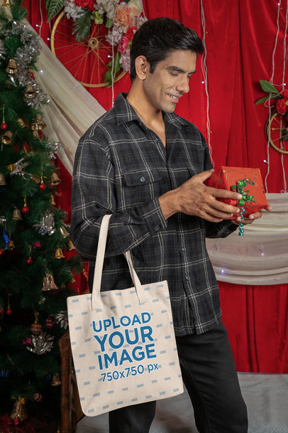 Tote Bag Mockup Featuring a Smiling Man Looking at a Christmas Present