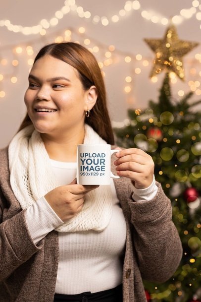 Mockup of a Happy Woman Holding a Mug Featuring a Blurred Christmas Tree