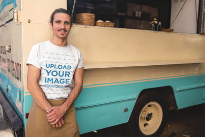 Man Wearing a Round Neck Tee Mockup Standing Against his Foodtruck