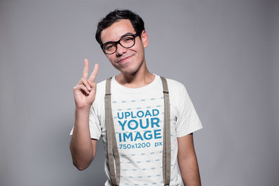 Smiling Nerd Wearing a T-Shirt Mockup and Suspenders Doing the Peace Sign