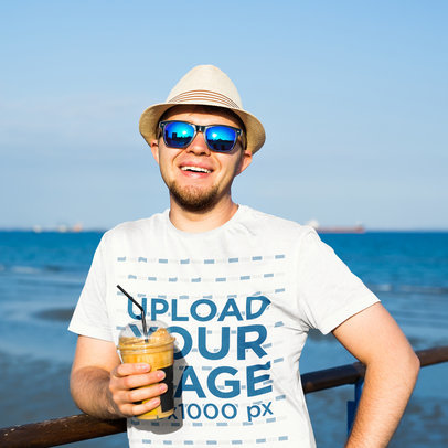 Round-Neck Tee Mockup of a Man with Sunglasses Posing on a Pier