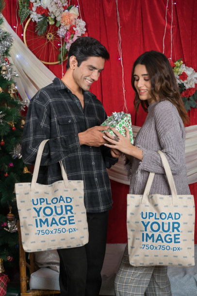 Tote Bag Mockup Featuring a Happy Couple Giving Each Other a Christmas Present