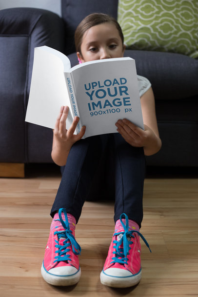 Mockup of a Girl Reading a Book While Sitting Against a Sofa