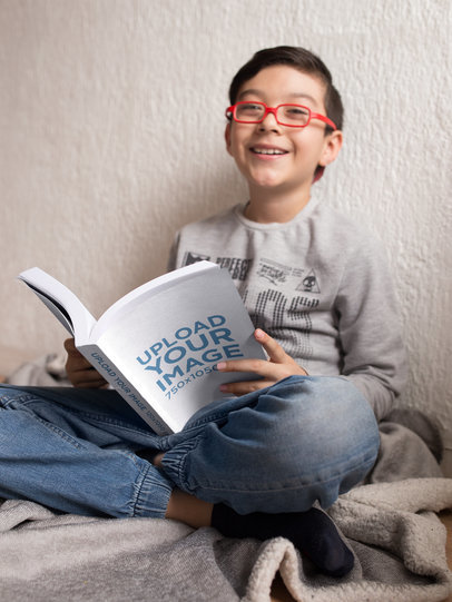 Mockup of a Happy Boy with Red Glasses Reading a Book in His Room