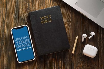 Mockup of an iPhone 13 Lying Next to a Bible