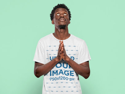 T-Shirt Mockup Featuring a Man Praying Against a Customizable Background