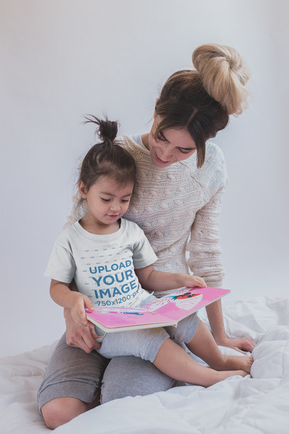 Girl Reading a Book Wearing a T-Shirt Mockup with her Mom Sitting on Bed