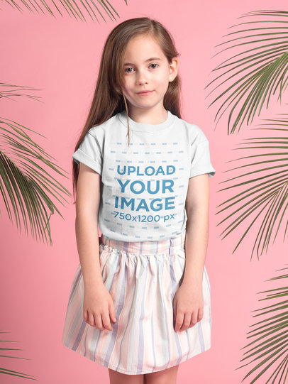 Little Blonde Girl Wearing a T-Shirt Mockup in a Pink Room with Green Leaves