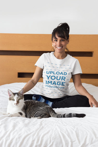 Portrait of a Happy Cat Owner Wearing a T-Shirt Mockup on Bed
