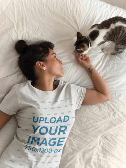 Tattooed Woman Wearing a T-Shirt Mockup Petting her Cat on the Bed