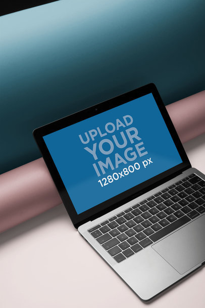 Mockup of a MacBook Placed Against Two Cardboard Tubes a20333