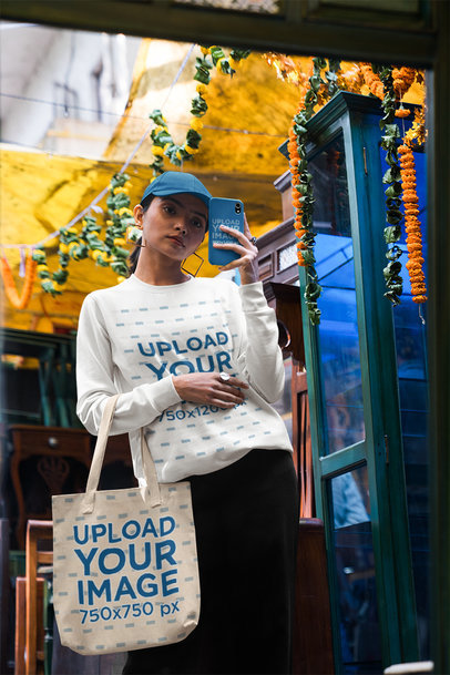 Phone Case and Tote Bag Mockup of a Woman Taking a Selfie in a Sweatshirt