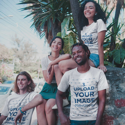 Interracial Group of Four Friends Living the Van Life Wearing T-Shirts Mockup Under Plants