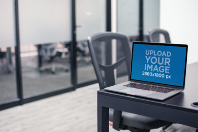 Mockup Featuring a MacBook Pro Placed by the Edge of a Meeting Room Table