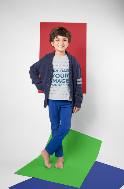Mockup of a Little Kid Posing Wearing a T-Shirt in a Photo Studio with Color Papers